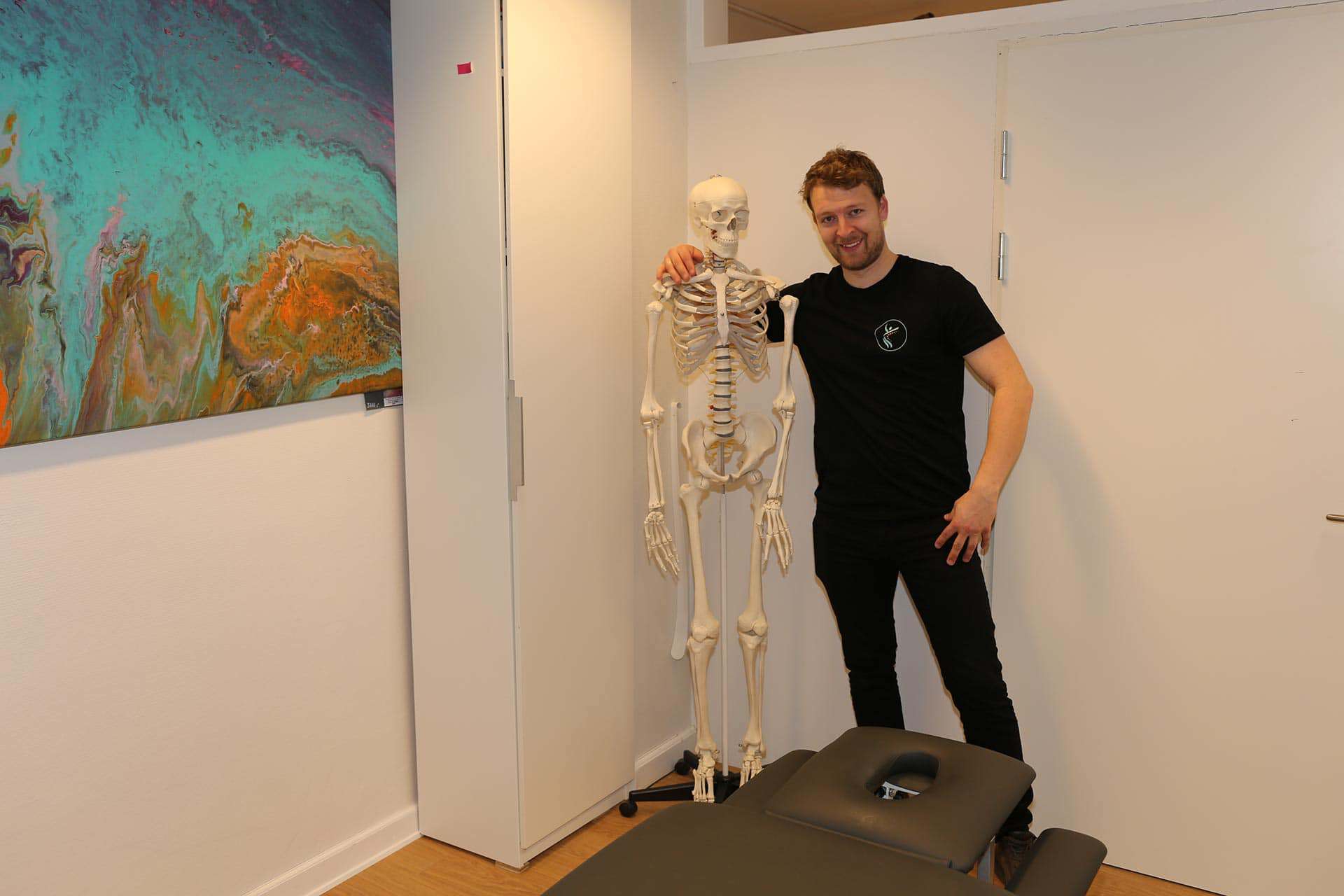 Fysioterapeut hos Klinik For Fysioterapi står ved skeletmodel