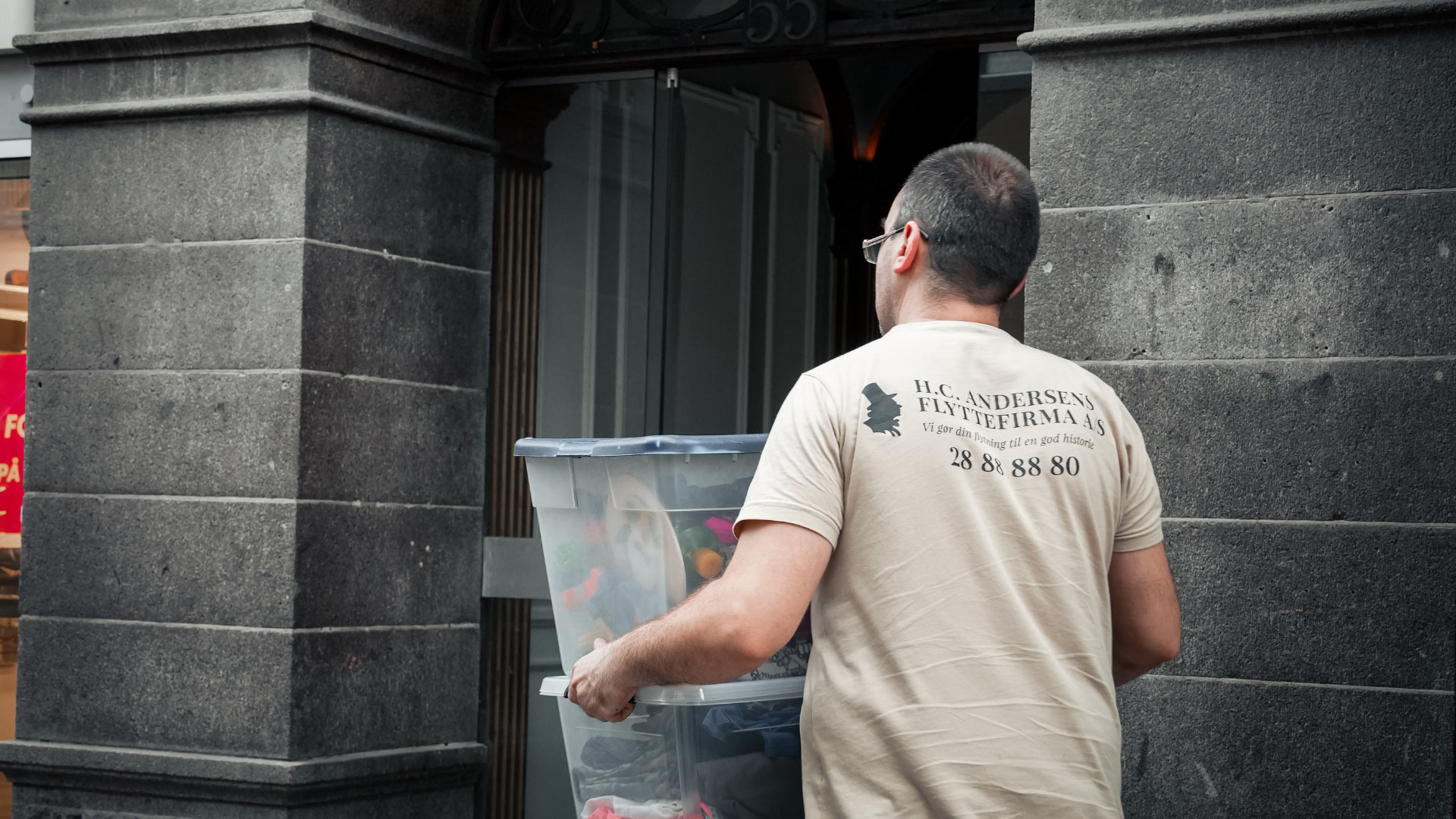 Alt-tekst: Mand med flyttekasse foran bygning, professionel flyttemand i København.