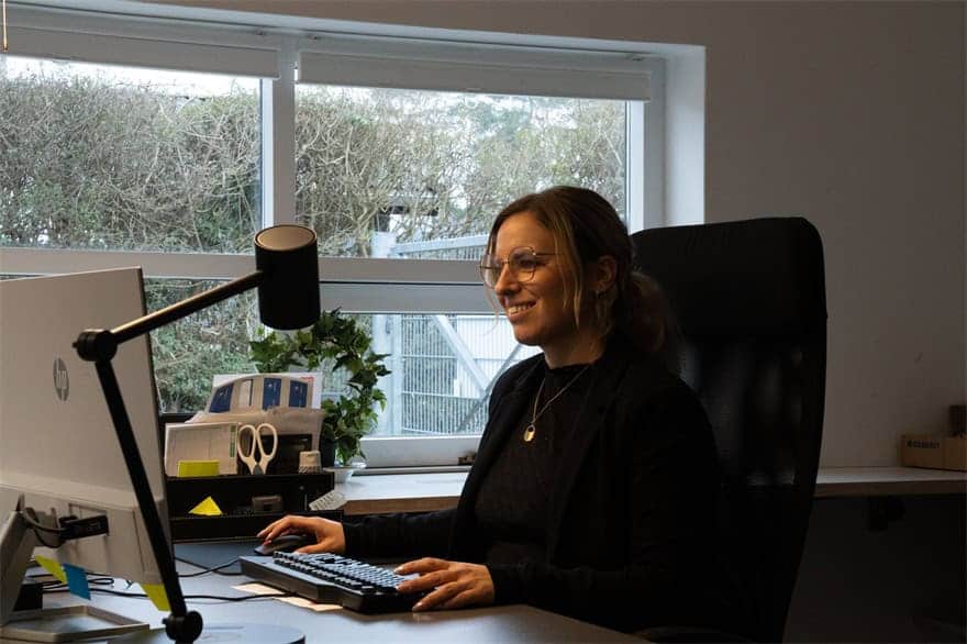 Kontormedarbejder hos K. Holmgreen & Søn taler i headset ved sin computer.