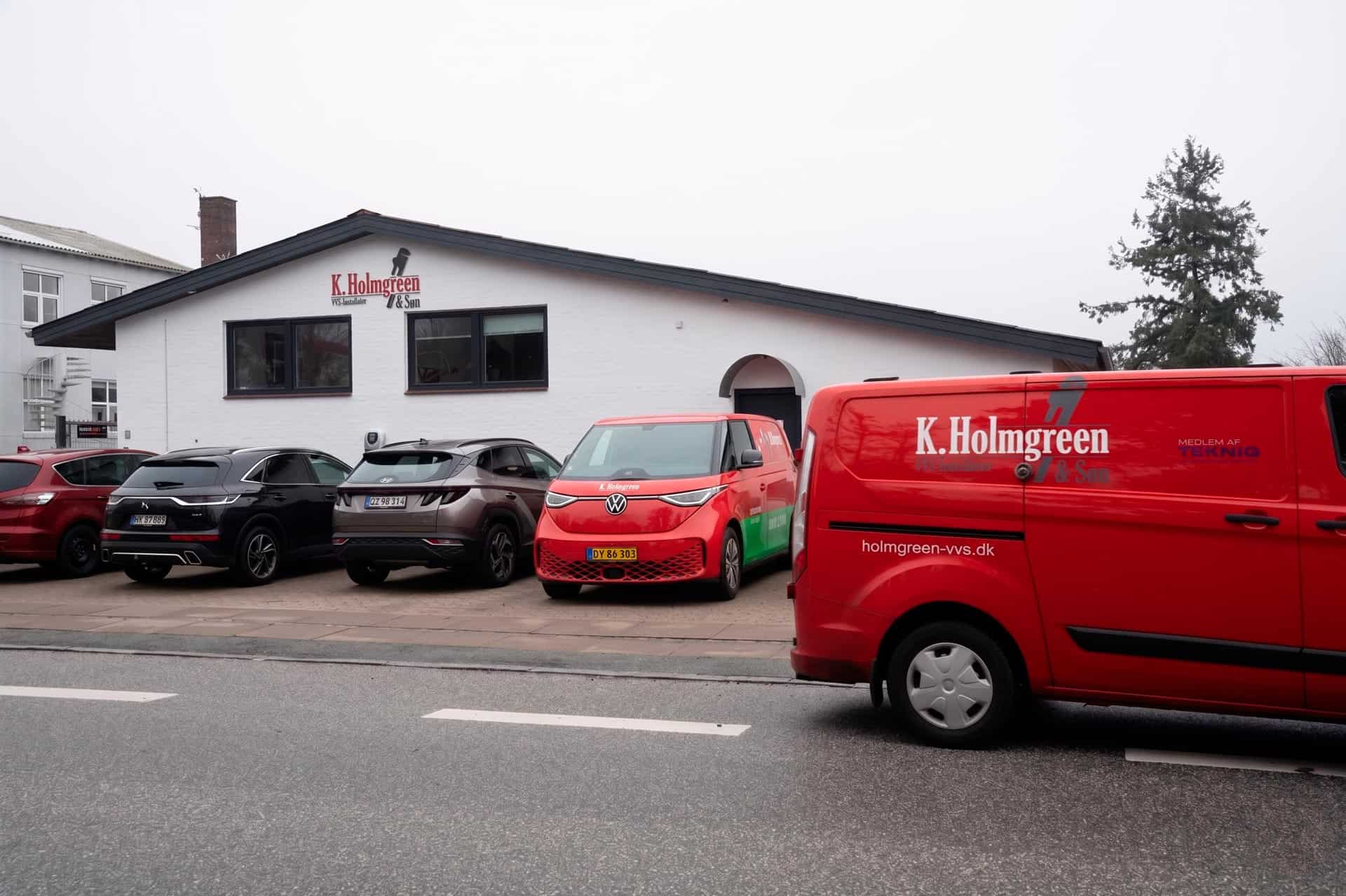 To røde varevogne parkeret foran VVS-firmaets bygning.
