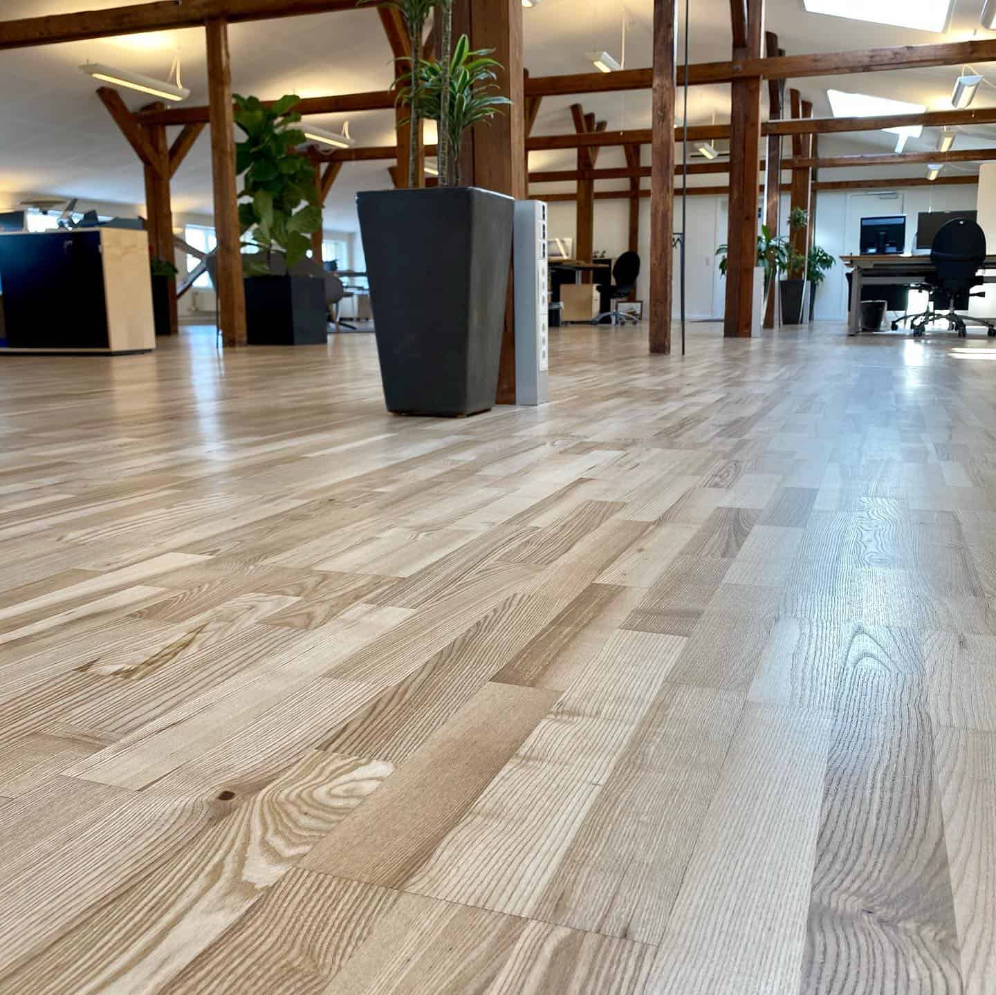 Parketgulv i et kontor set fra en vinkel, der fanger dele af kontorinventar.