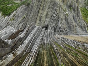 Rigid layers of rock at the base of steep hill. Edward Burtynsky, China Recycling.