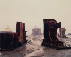 Rusting shipwreck pieces on muddy ground. Edward Burtynsky, Shipbreaking