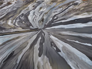 Aerial view of a road ending at the convergence of flowing, grey-toned terrain. Edward Burtynsky, African Studies series.