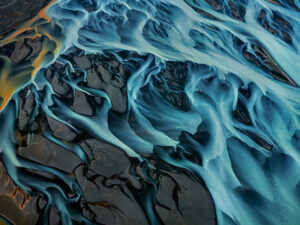 Aerial view of a vividly colored orange and blue braided river. Edward Burtynsky, Water series.