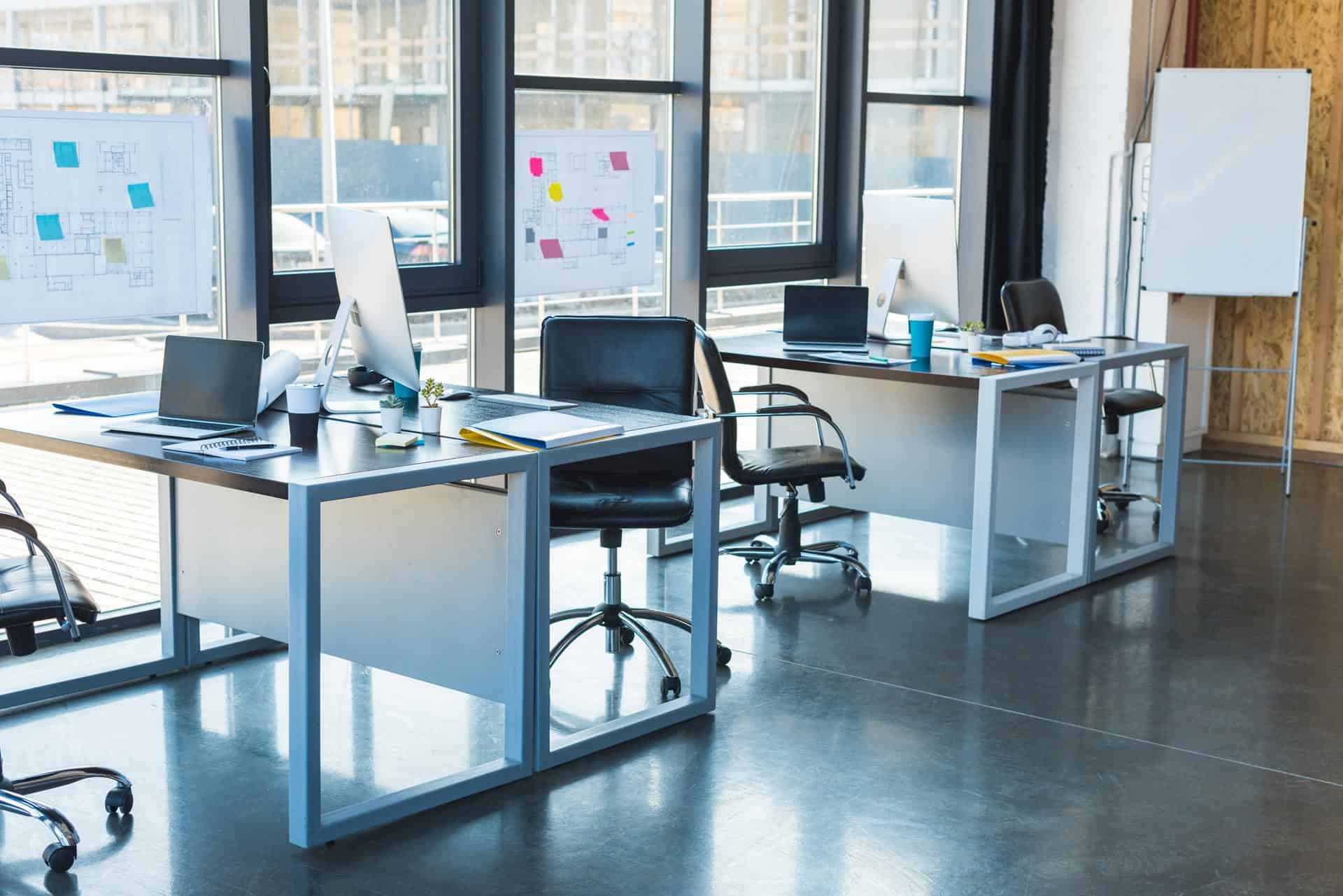 Ryddeligt kontor med skriveborde og whiteboard klar til arbejdsdagen.