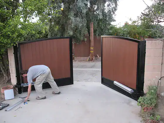 Man installing swing gate operators on a driveway gate