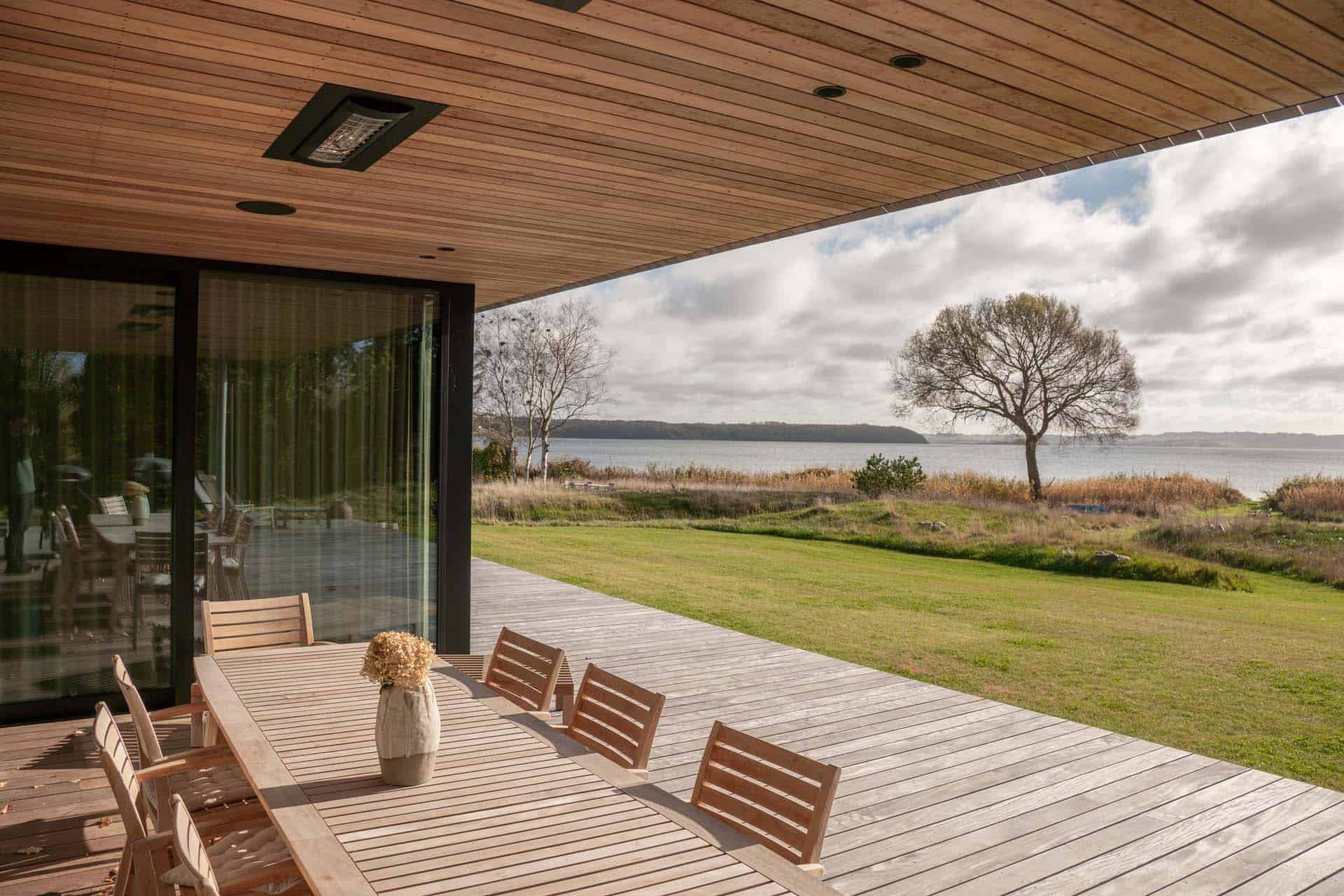 Overdækket terrasse med træloft og kig til marker.