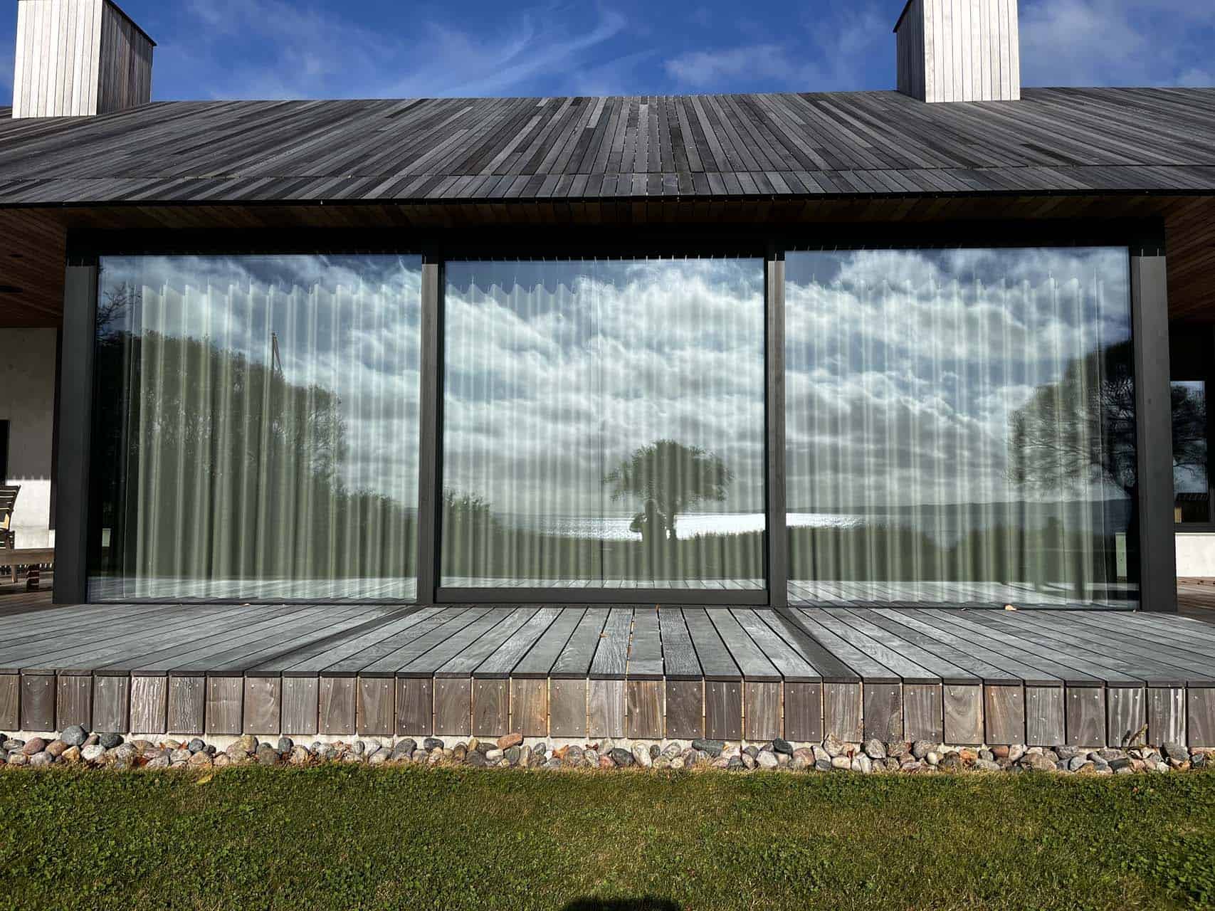 Store vinduesruder, der reflekterer hav og himmel.