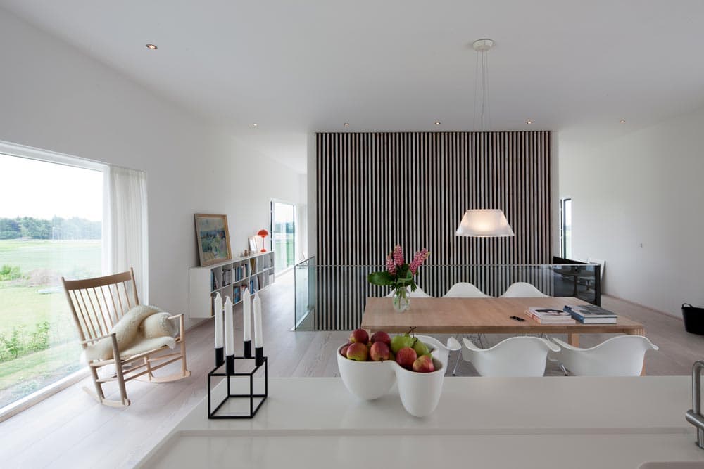 Spiseområde med store vinduespartier i moderne hvid villa.