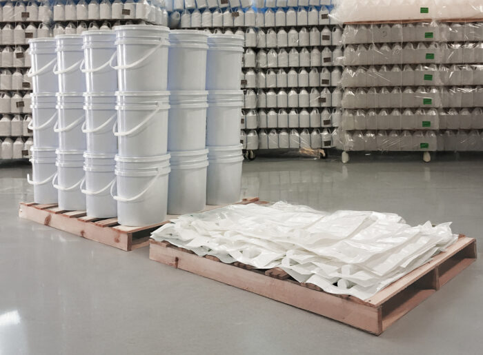 White plastic buckets stacked on warehouse pallets