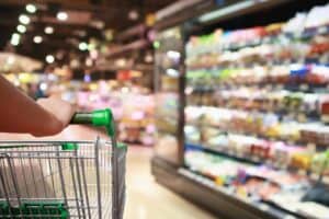 Person pushing shopping cart in grocery store aisle