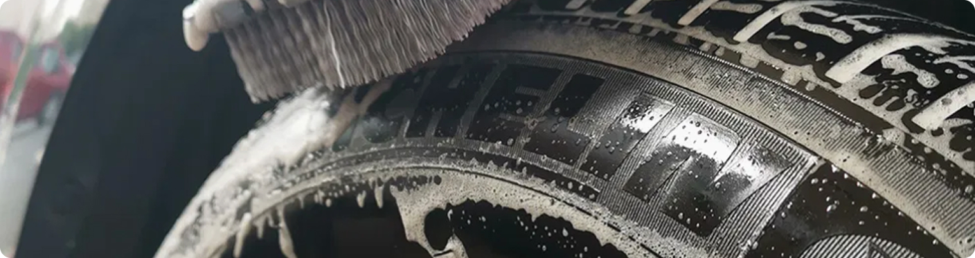 Close-up of car tire being scrubbed with brush