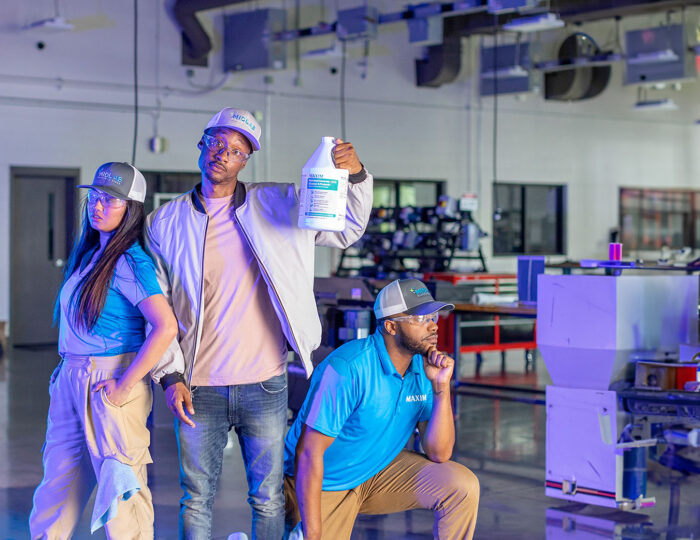 Three industrial workers holding cleaning solution in factory