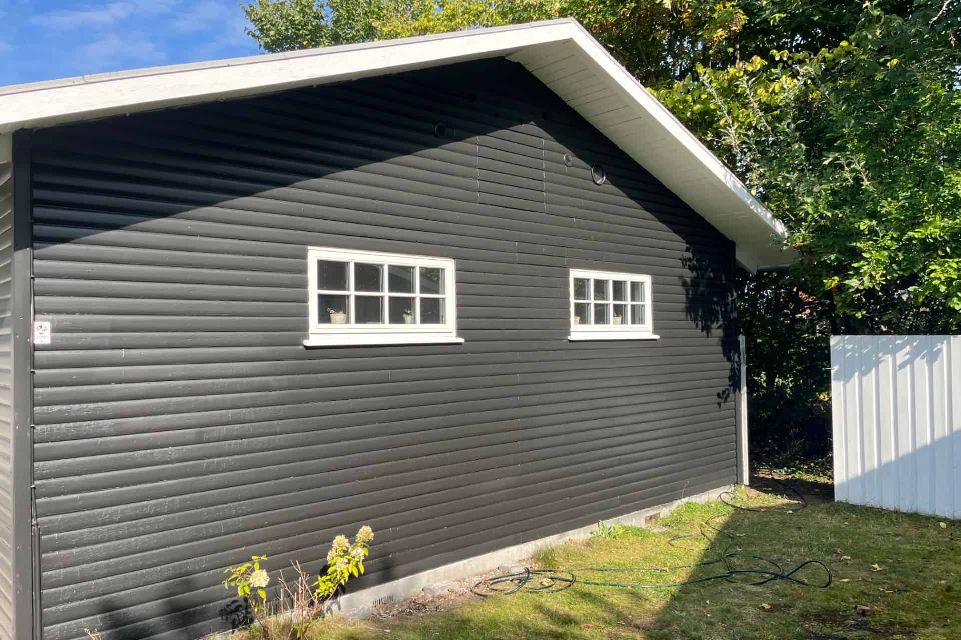Detalje av nymalet sort træbeklædning og hvidt vindue