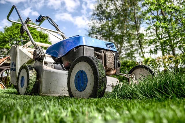 Blue lawnmower resting in the green grass