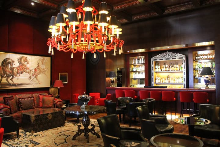 Deep red walls, a built-in bar, and leather chairs complement this Chinese style dining room and bar atmosphere.