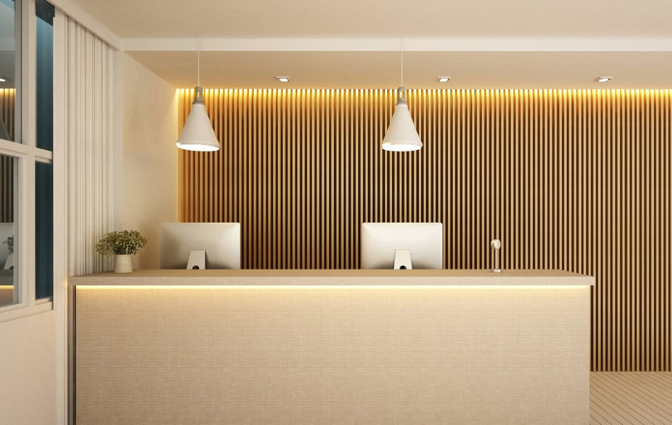The front desk at a sleek and modern hotel is equipped with two computers. Nobody sits at the desk.