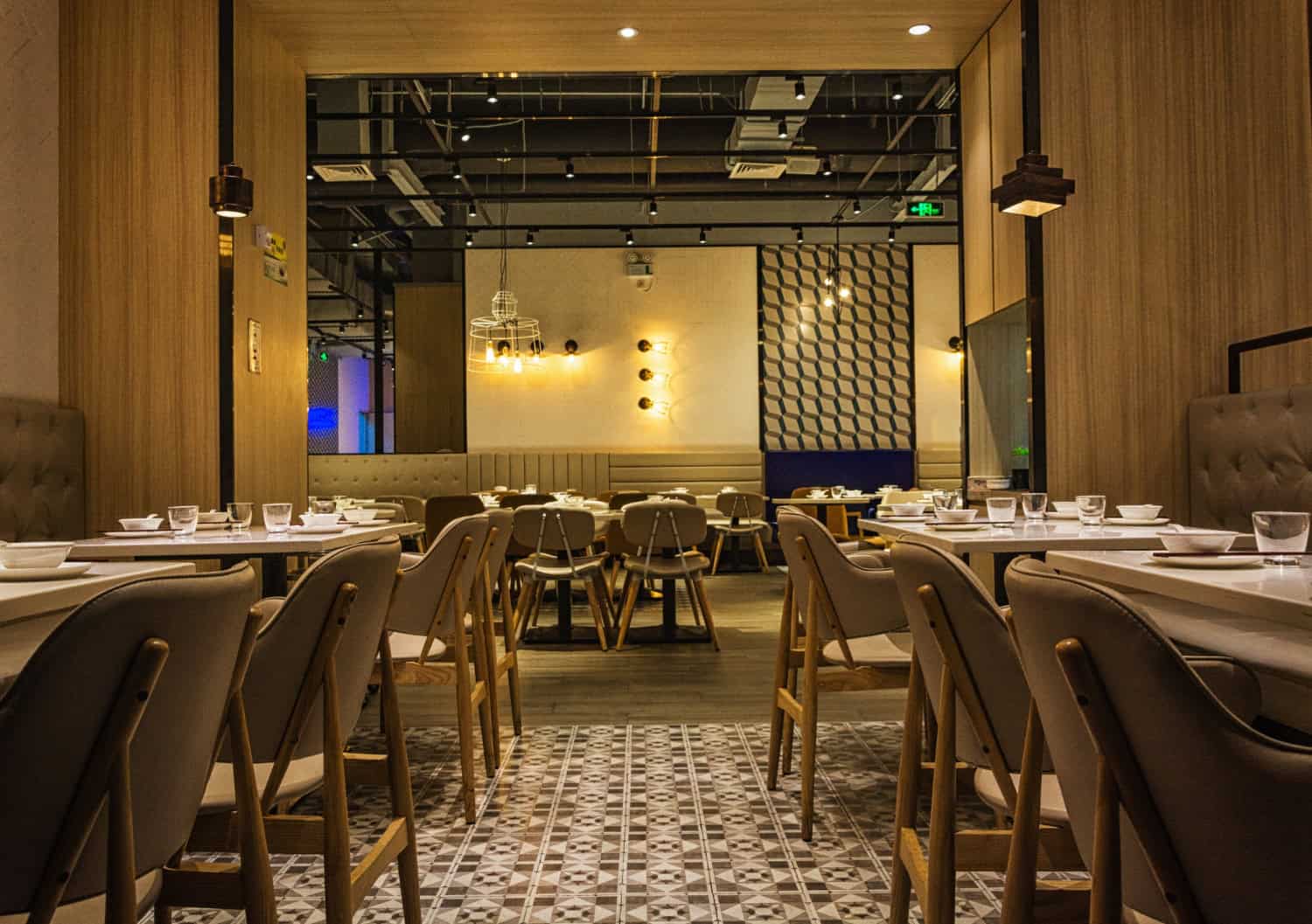 An empty restaurant with set tables, chairs, and industrial decor.