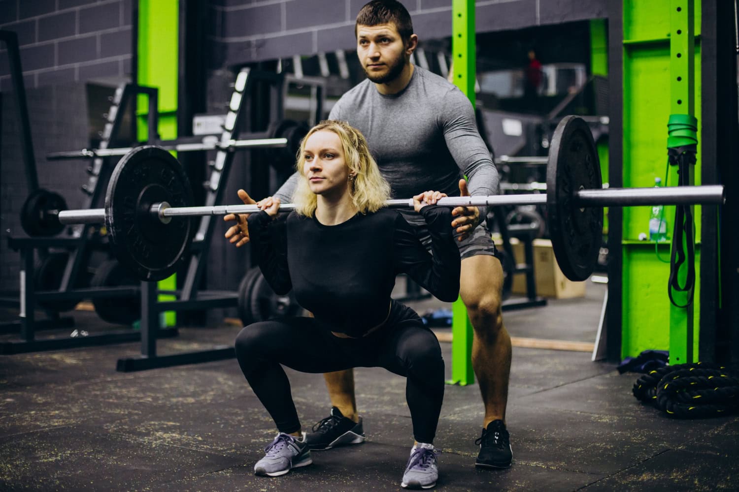 A gym staff trainer works with a client, training on weight lifting.