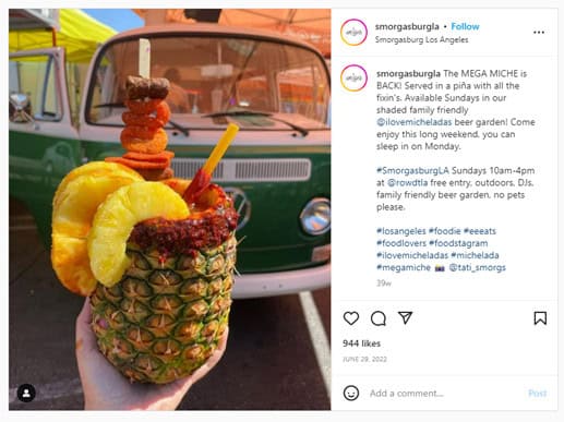 A screenshot of an Instragram post from SmorgasburgLA showing a unique cocktail. A woman's hand holds a pineapple drink that's garnished with spicy pineapple slices and other garnishes.