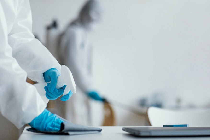 Frozen food production workers in protective coverings sanitize work areas.