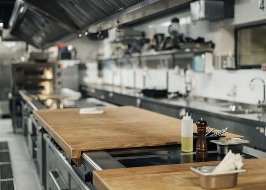 A long view of a counter in an empty professional kitchen. Sustainable restaurant equipment can significantly decrease costs.