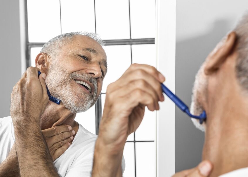 A senior citizen smiles into the mirror as he shaves. The hot water recovery rate ensures he has hot water for bathing and hygiene. 