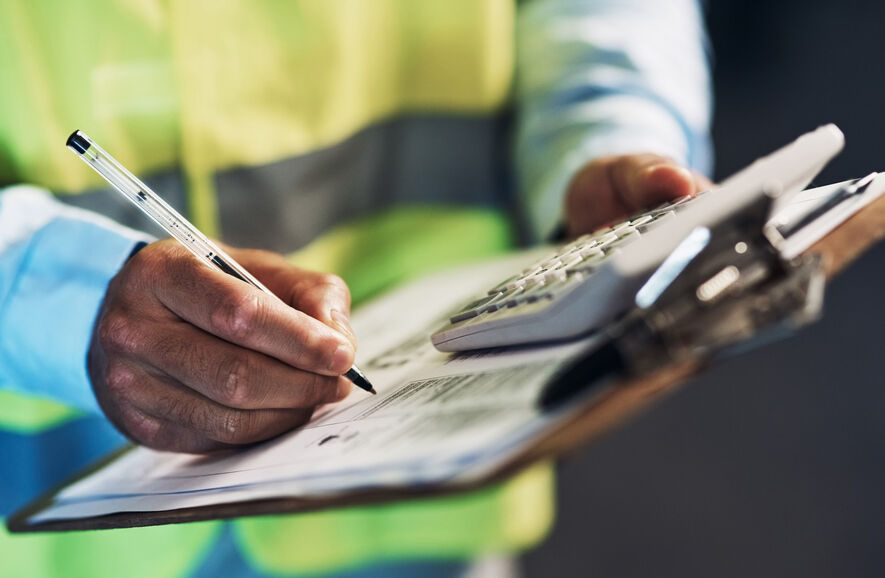 The hands of a safety inspector are marking off boiler safety features required in many states on a form attached to a clipboard.