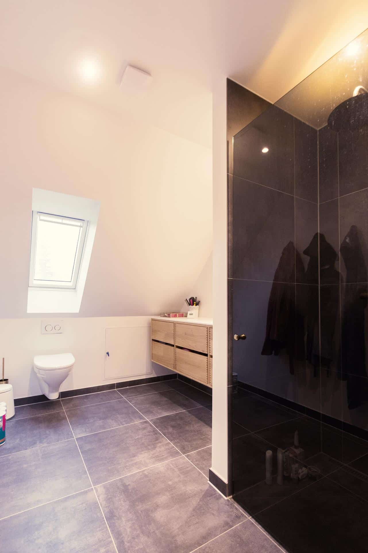 Badeværelsesrenovering udført med store fliser og glasvæg ind til badet