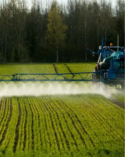 Aerial crop spraying machinery in action over a green field.