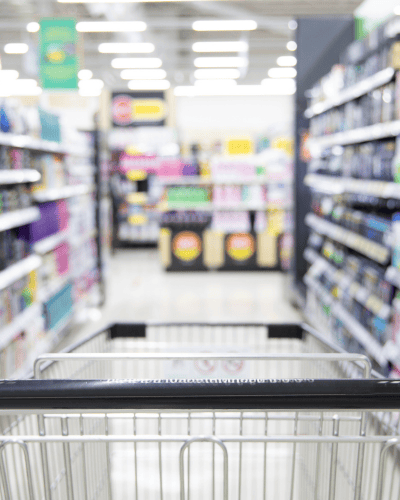 Consumer packaged goods aisle in a retail store with shopping cart.