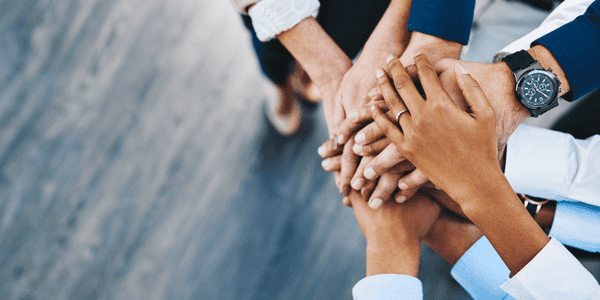 Diverse team members stacking hands in a business meeting.