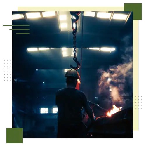 Industrial worker operating machinery in a factory environment with safety gear.