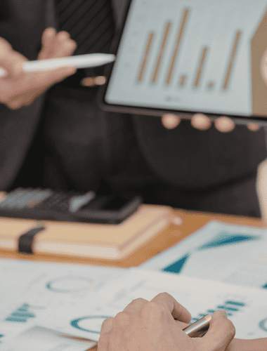 Business professionals analyzing pricing and revenue data on digital devices.