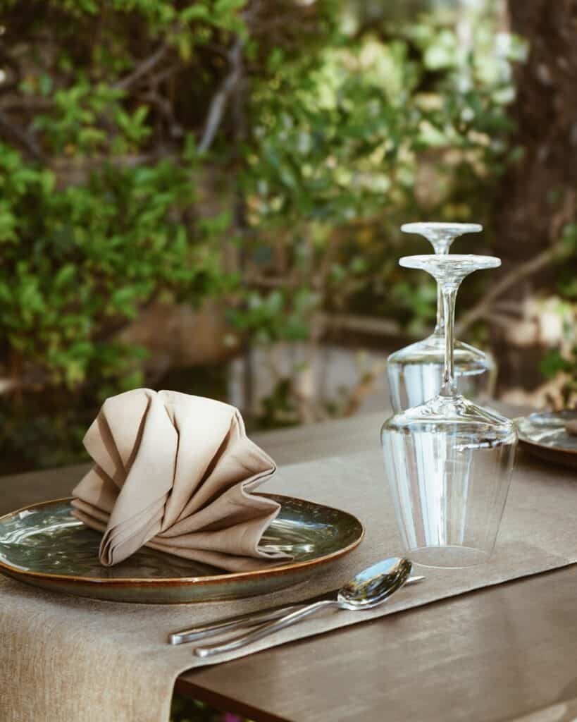 Upscale table setting with glassware, napkin, and cutlery in outdoor dining area.