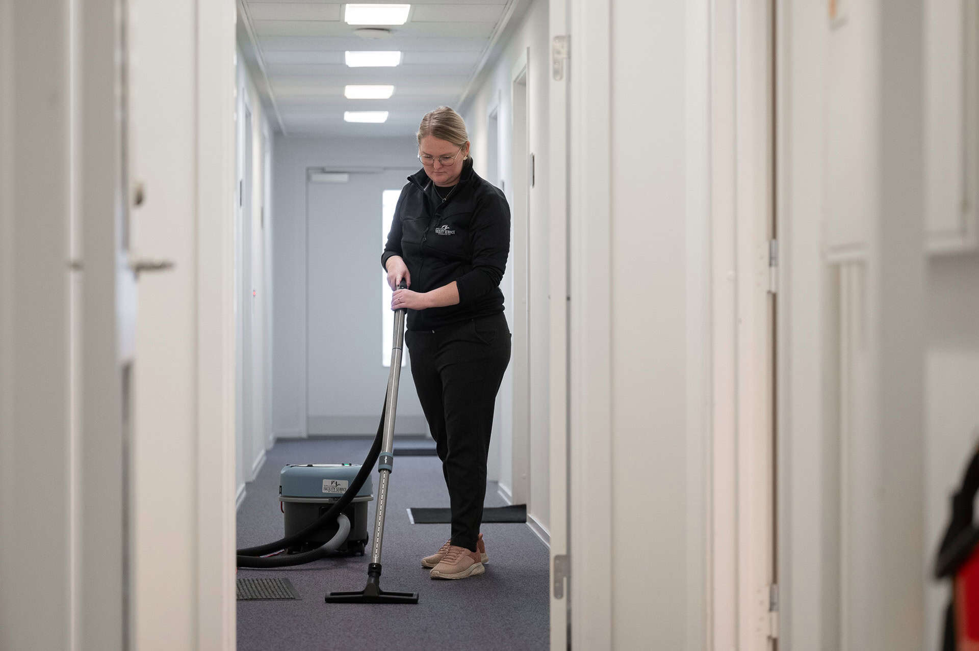 medarbejder støvsuger gulv i forbindelse med erhvervsrengøring hos en kunde