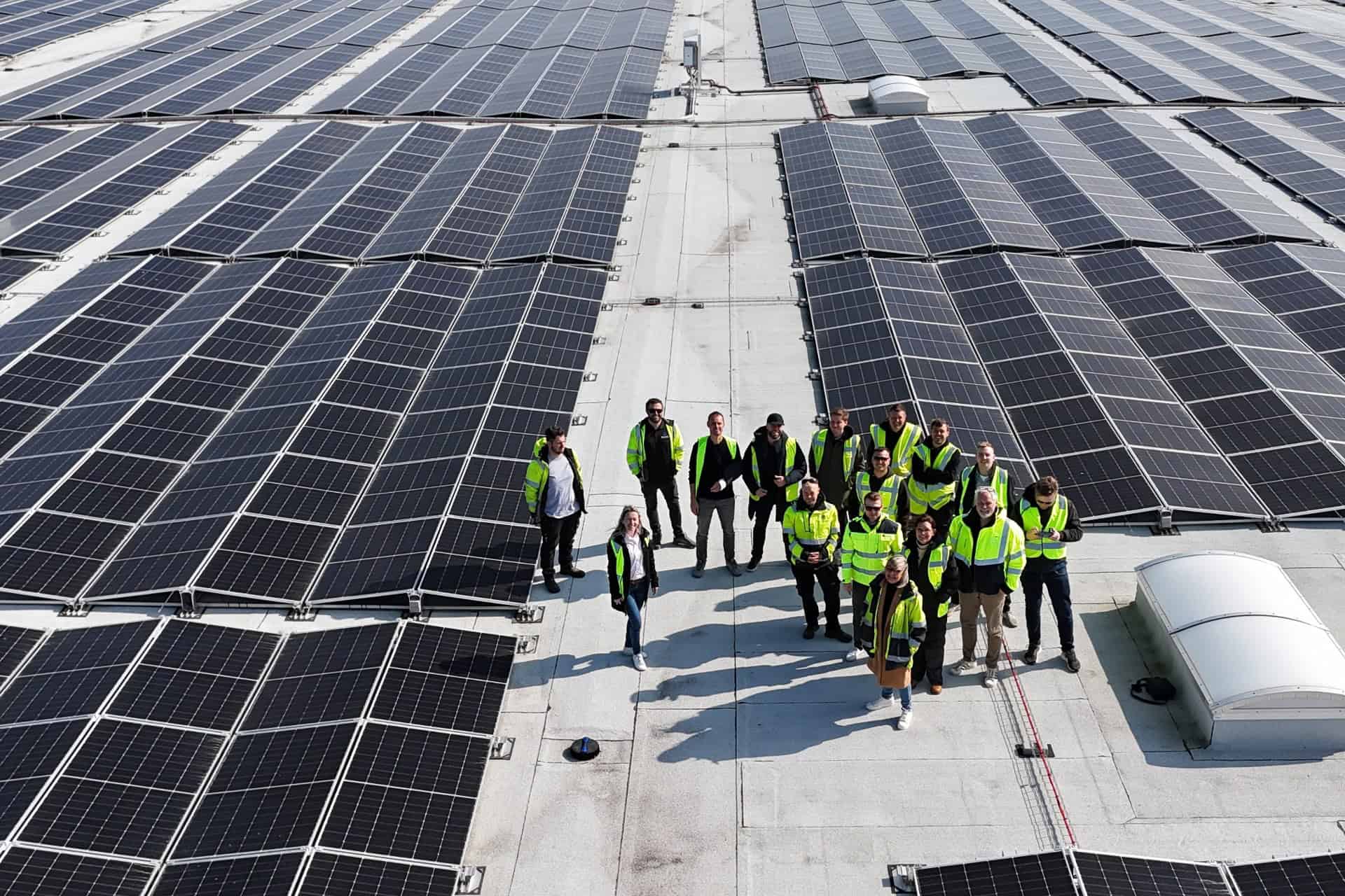 Team af teknikere foran solcellepaneler på tag.