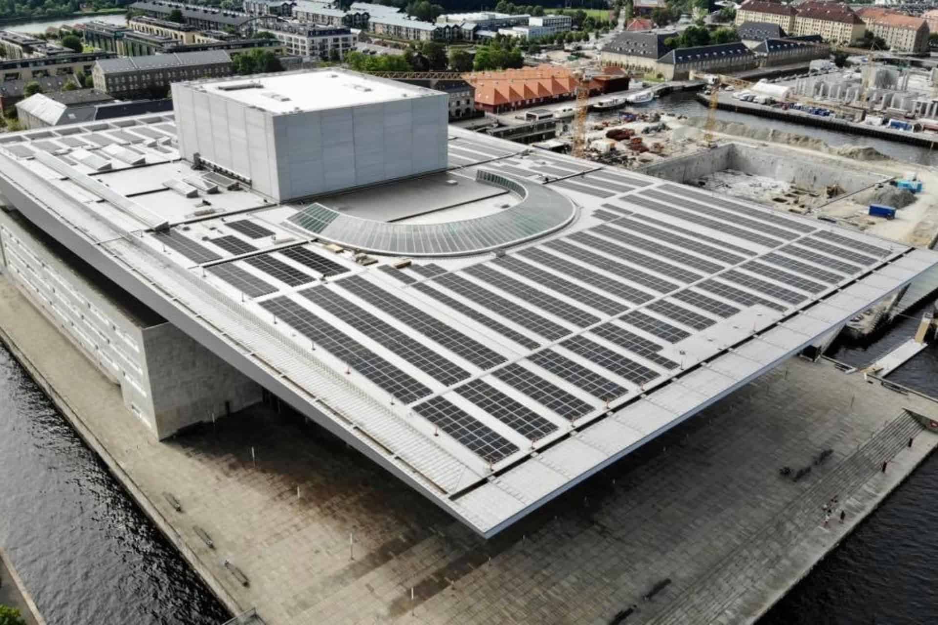 Stort solcelleanlæg installeret på tagflade i byområde.