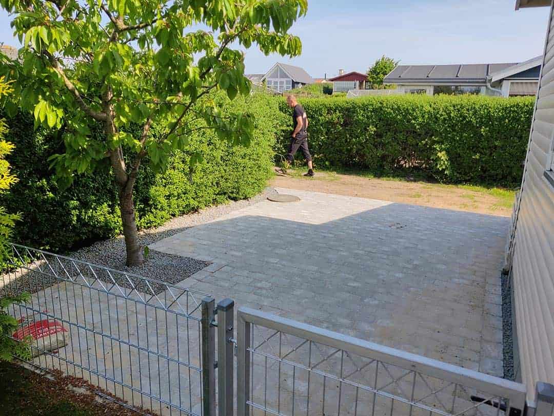 Fliseareal med udskæring til træ udført som brolægning på Sjælland.
