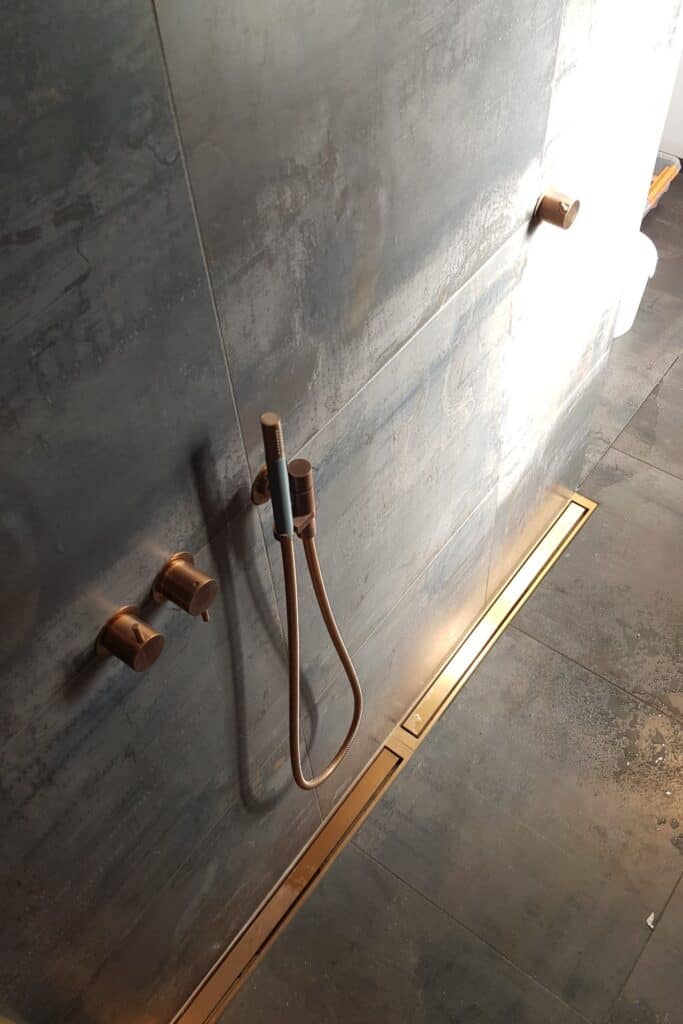 Bruseniche med mørke vægge, kobberarmatur og aflang messingrist.