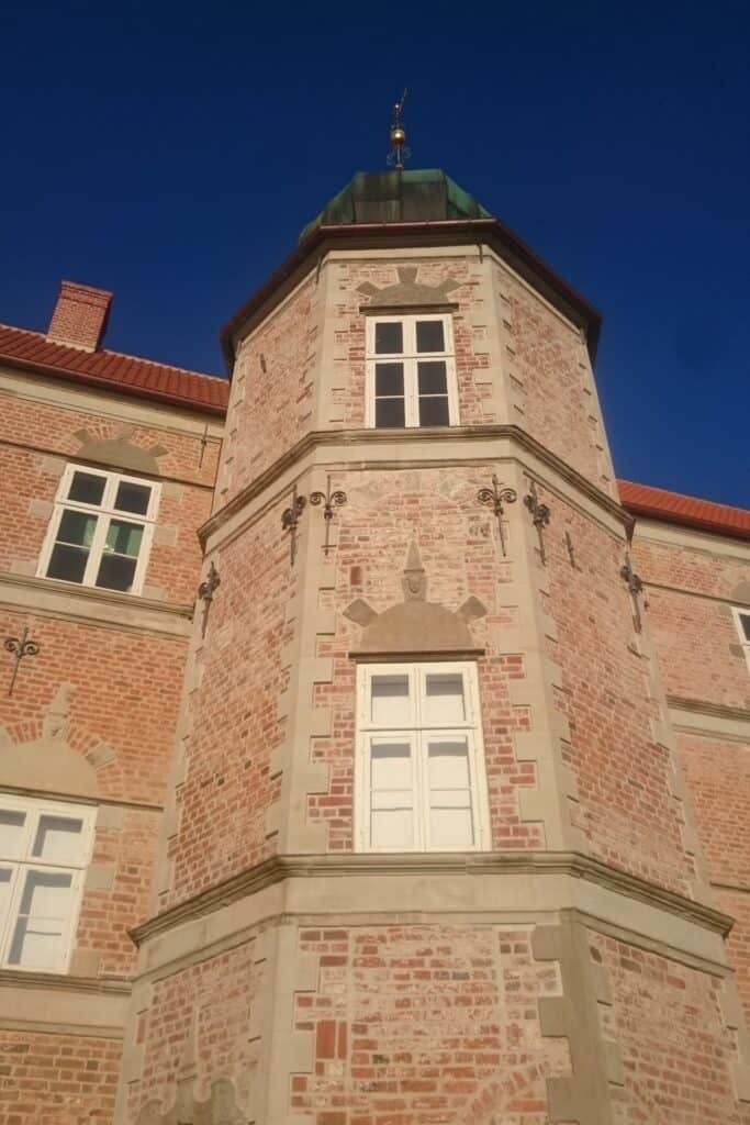 Rød murstensfacade med lyse vinduer på et slot.