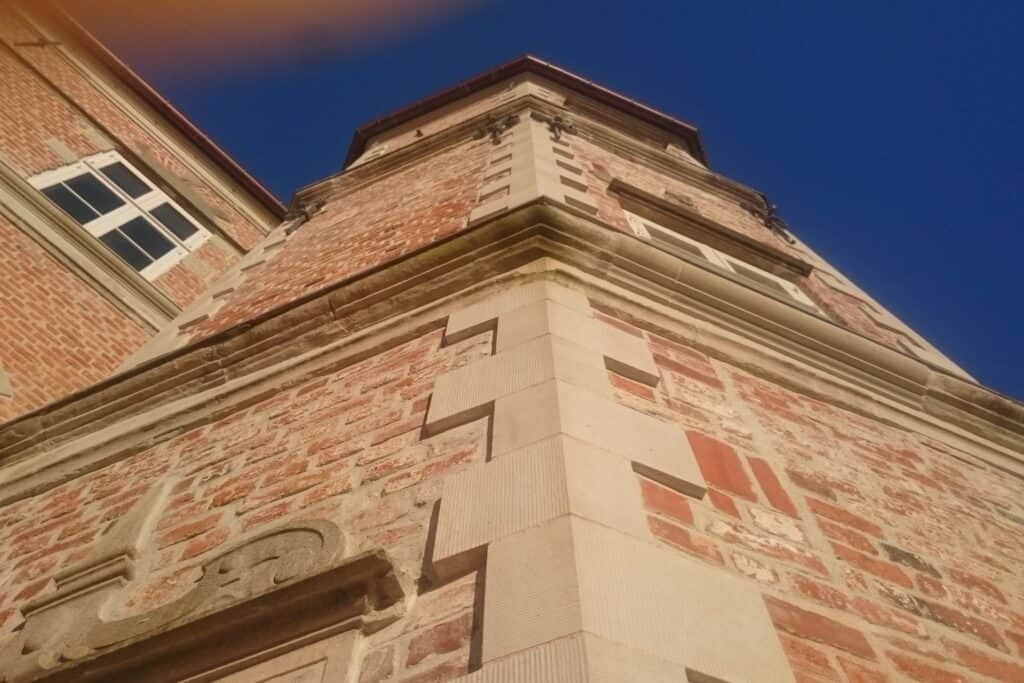 Hjørnet af en ældre bygning med mønstret murværk af røde sten.