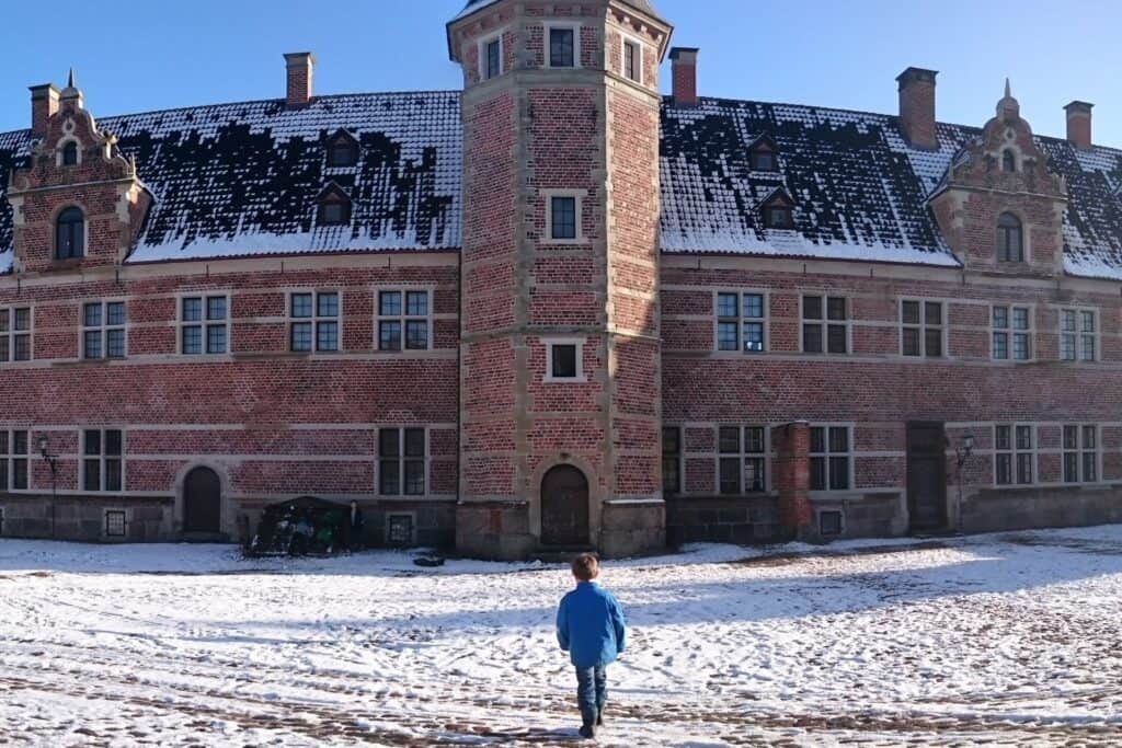 Stort slot i røde mursten dækket af sne.