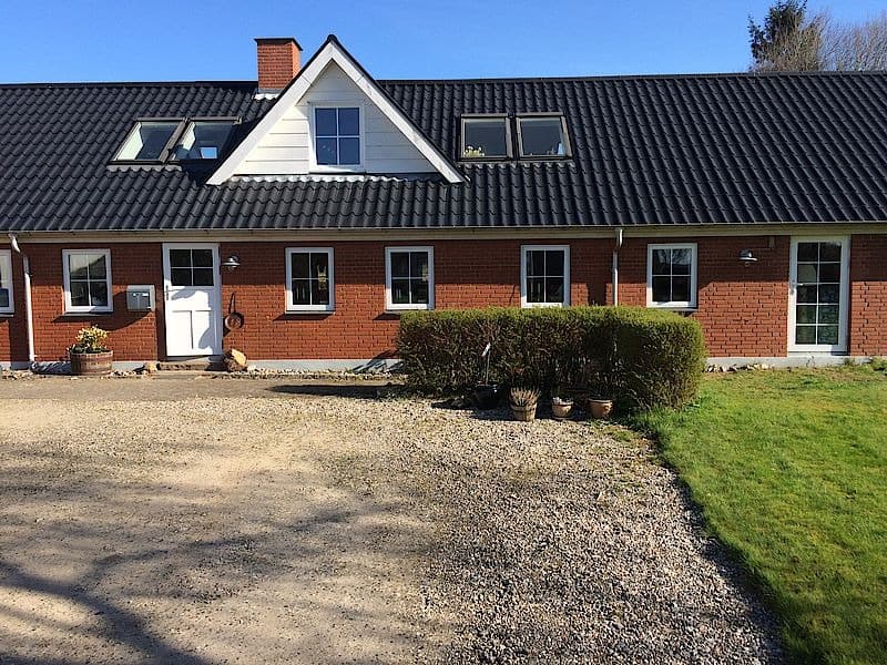 Parcelhus i røde mursten med sort tag og en hvid tagkvist.