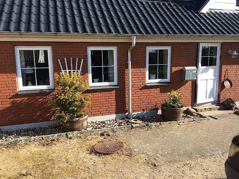 Facade af røde mursten med hvide vinduer og planter i krukker.