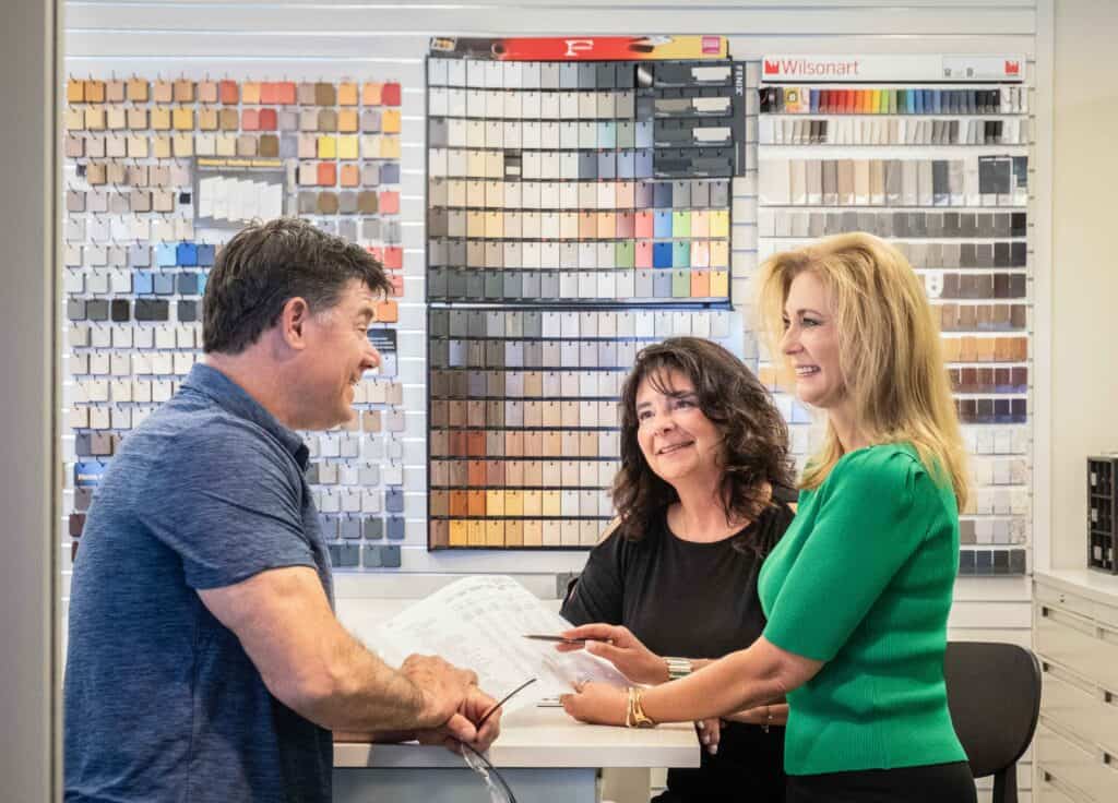 Three people are standing around a table having a meeting