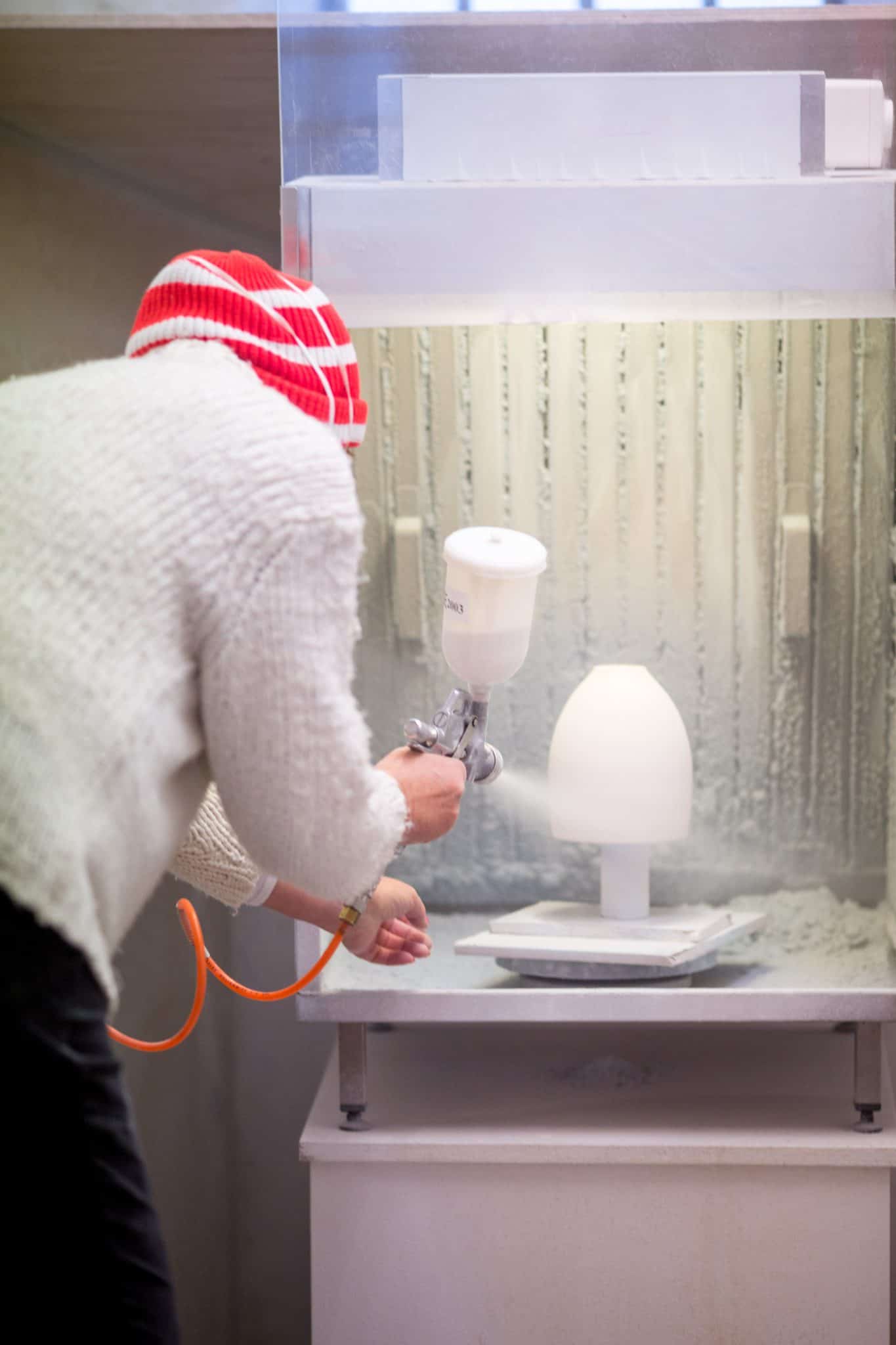 Person arbejder i keramikværksted med sprayflaske og keramiske værktøjer.