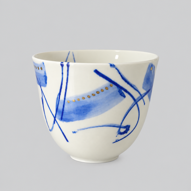 Keramisk kop med blå dekor og gulddetaljer, kunstnerisk design.