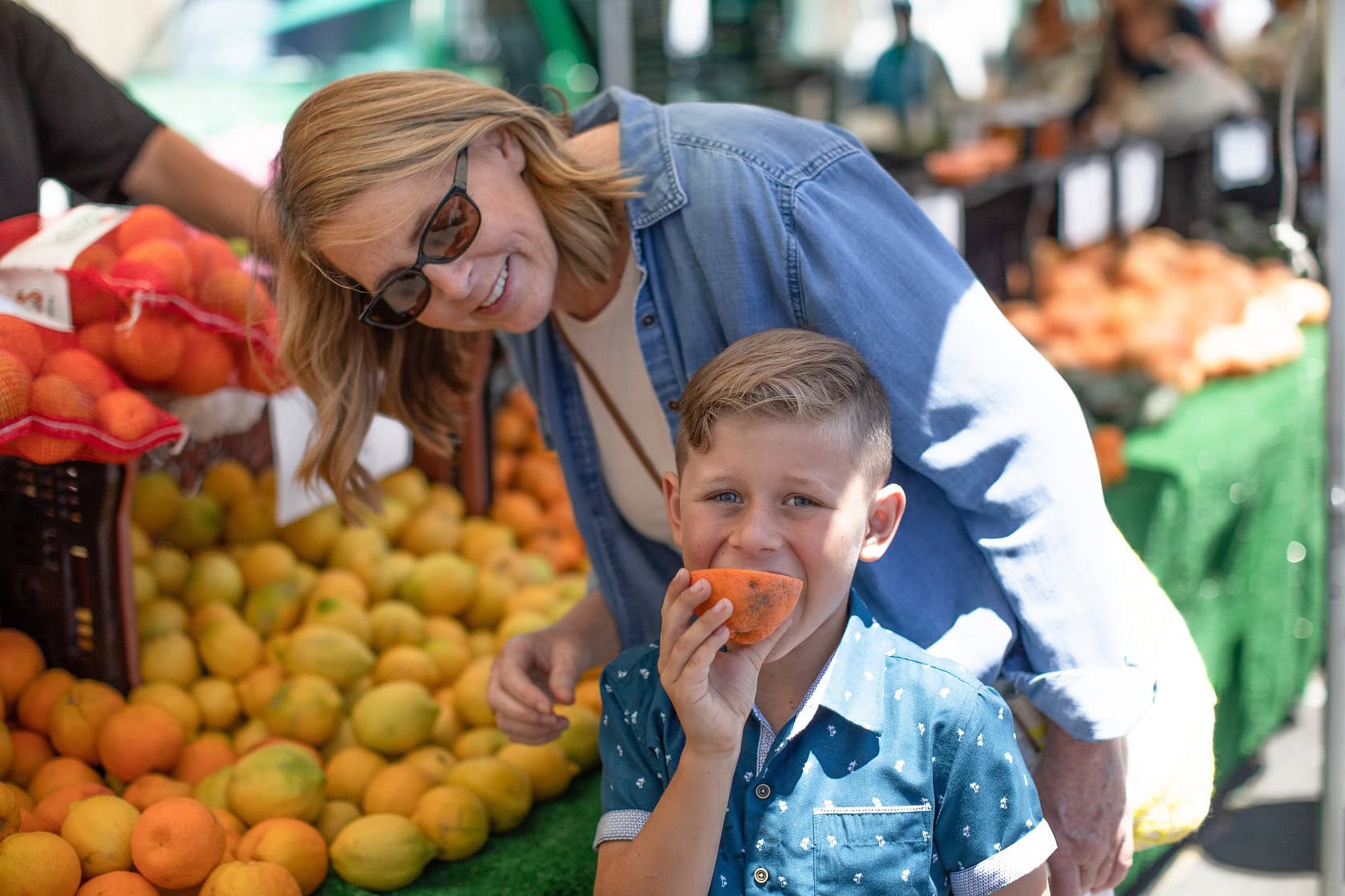 Mom watches as a young boy samples fresh citrus
